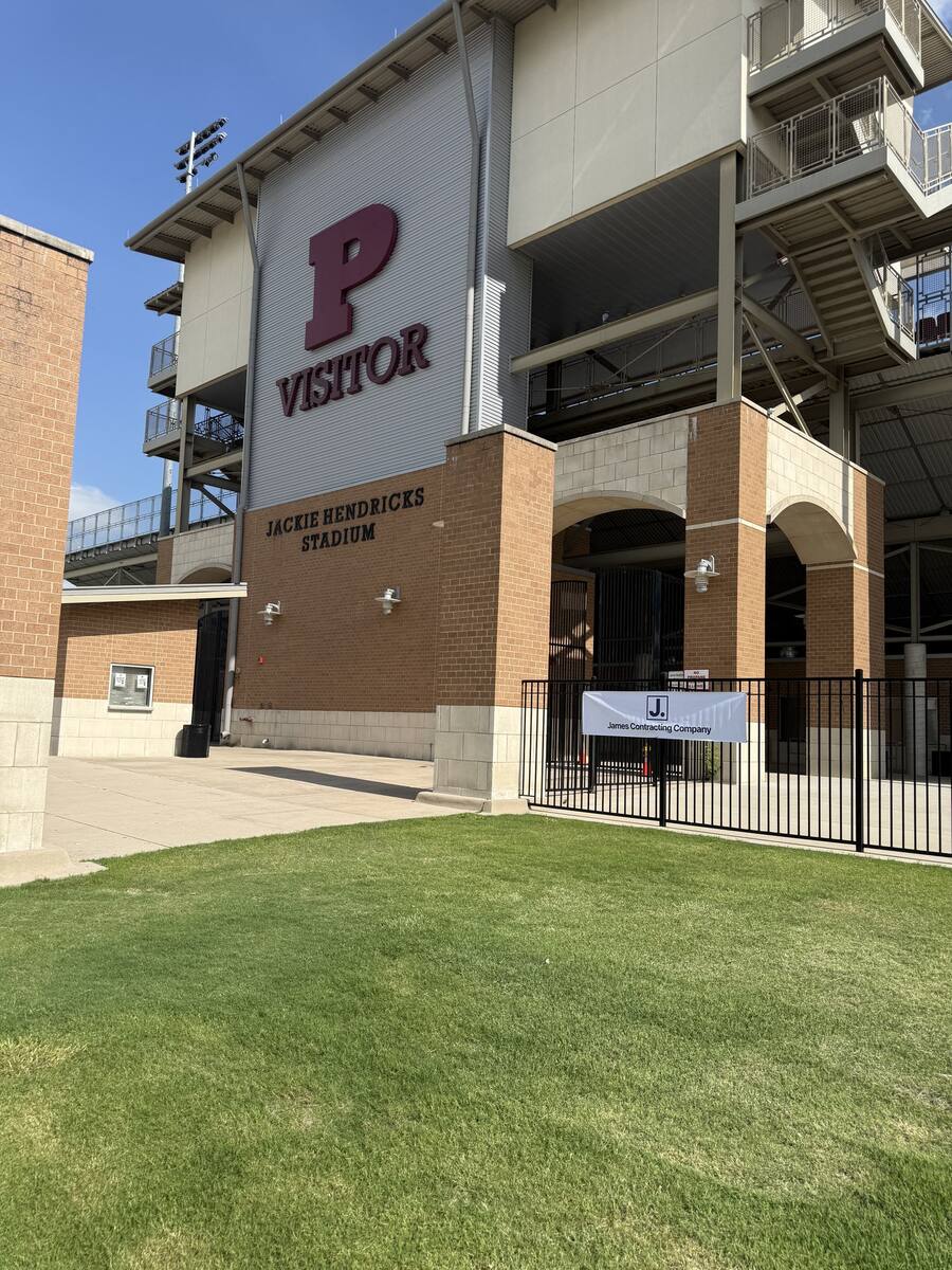 Visitor side of Jackie Hendricks Stadium with a James Contracting Company banner on the fence